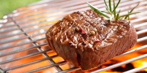 A thick strip steak being grilled outdoors